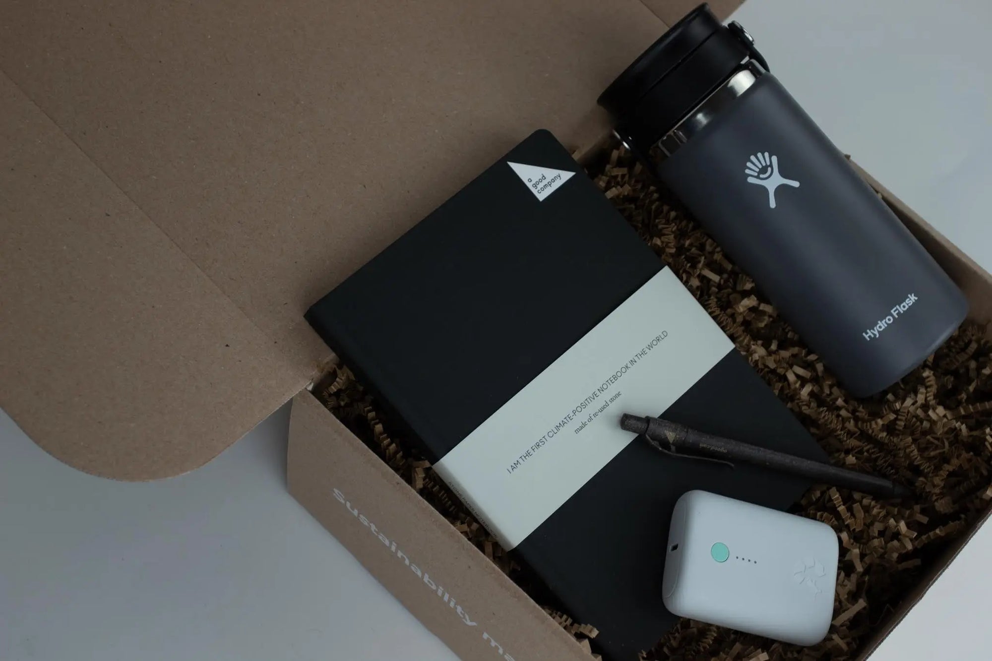 Eco-friendly gift biox that includes a notebook, pen, coffee packages, and tin pint.